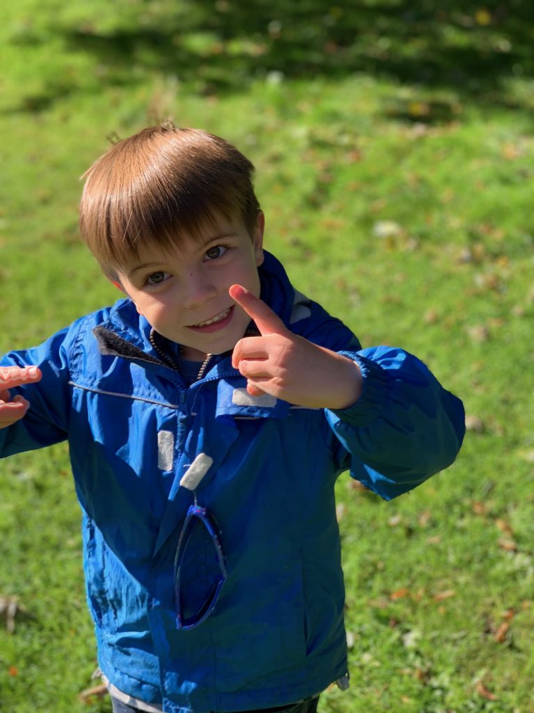 young boy shows delight in collectting conkers from the ground