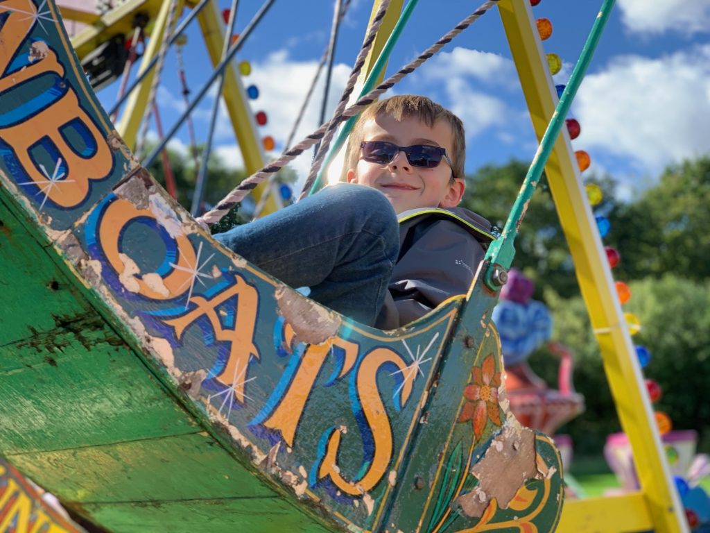 7 year old boy sits in a swing boat with a smile on his face